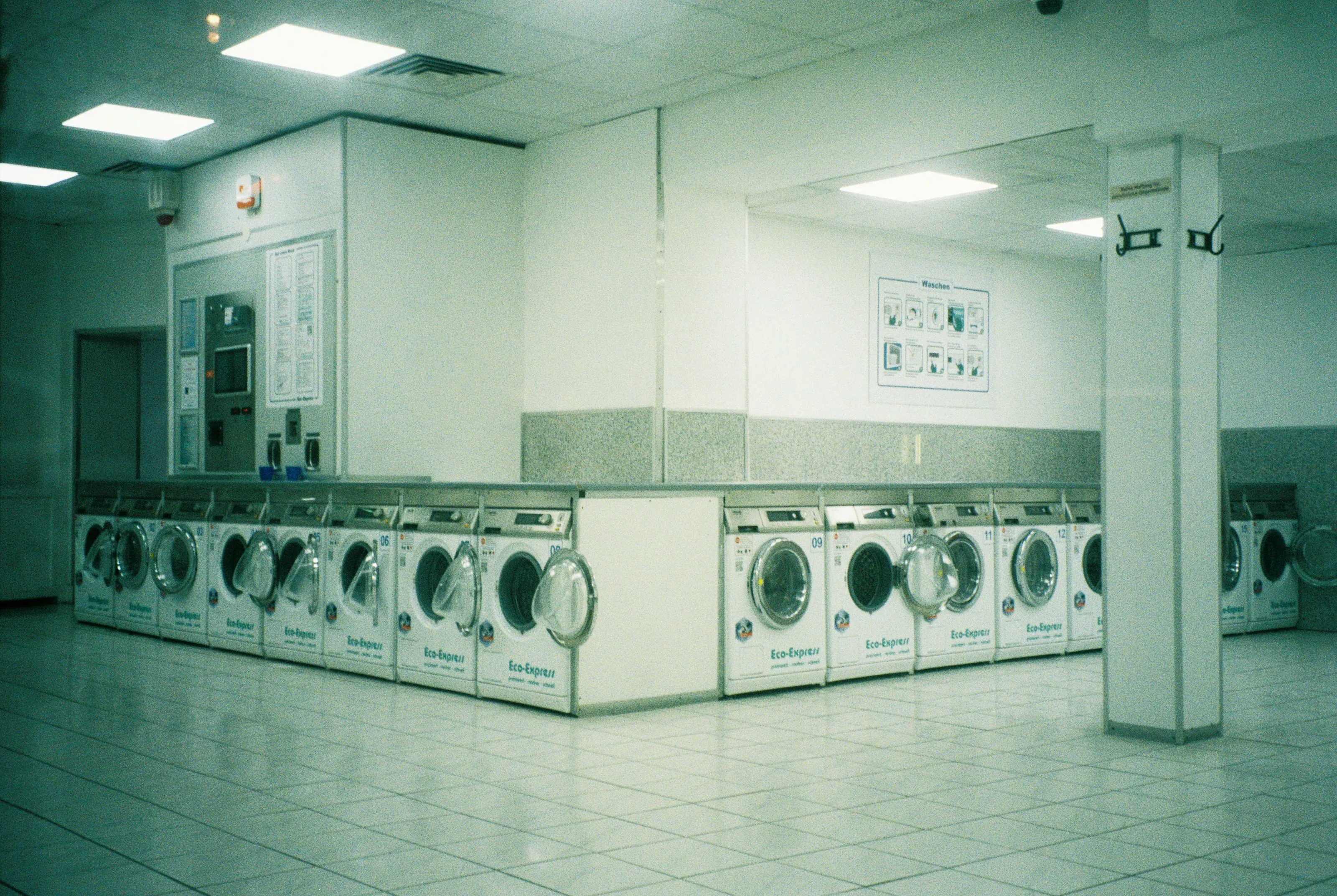 A long row of front-loading washers in a bright laundromat