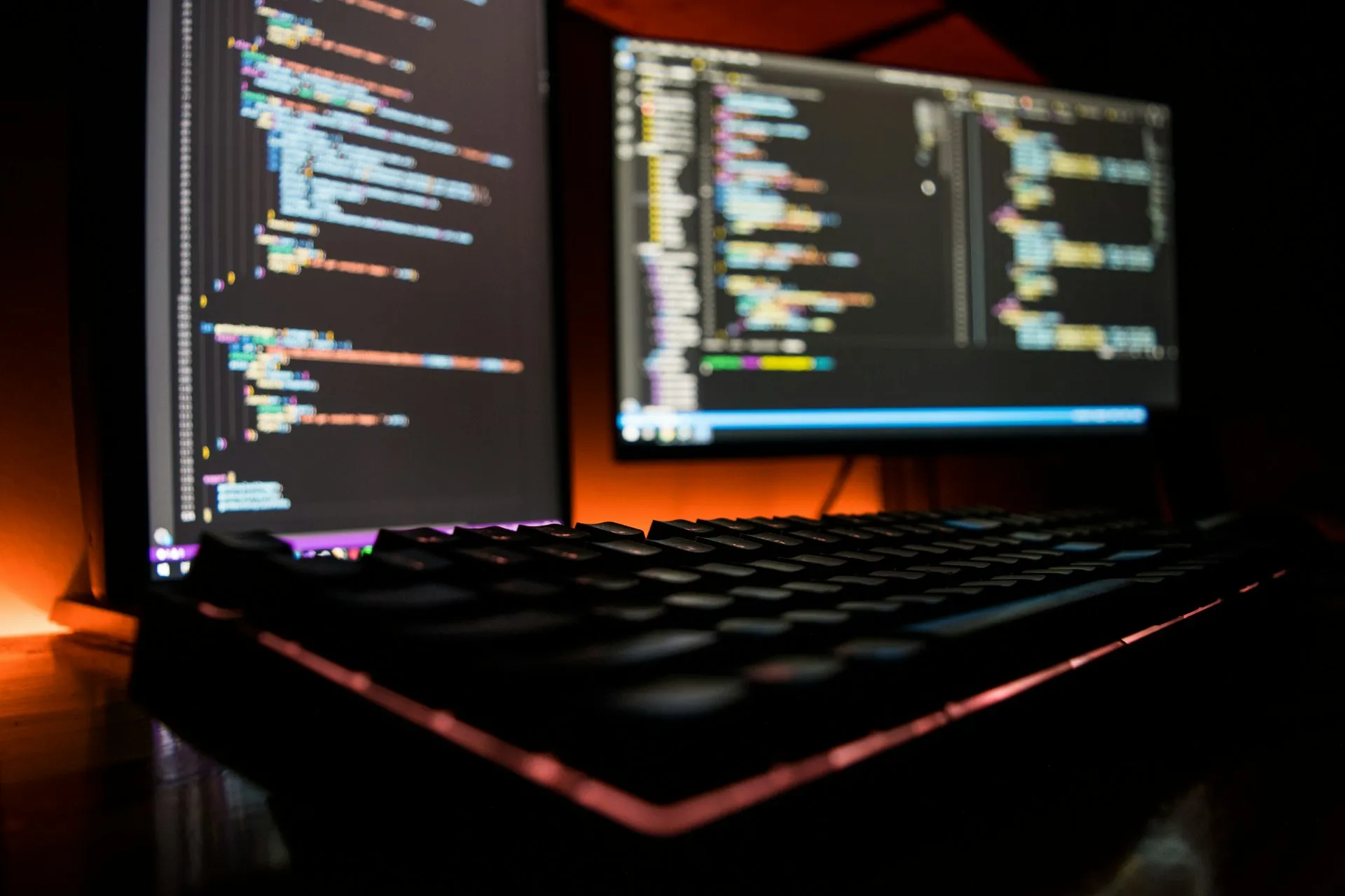Code on two monitors in a dark workspace