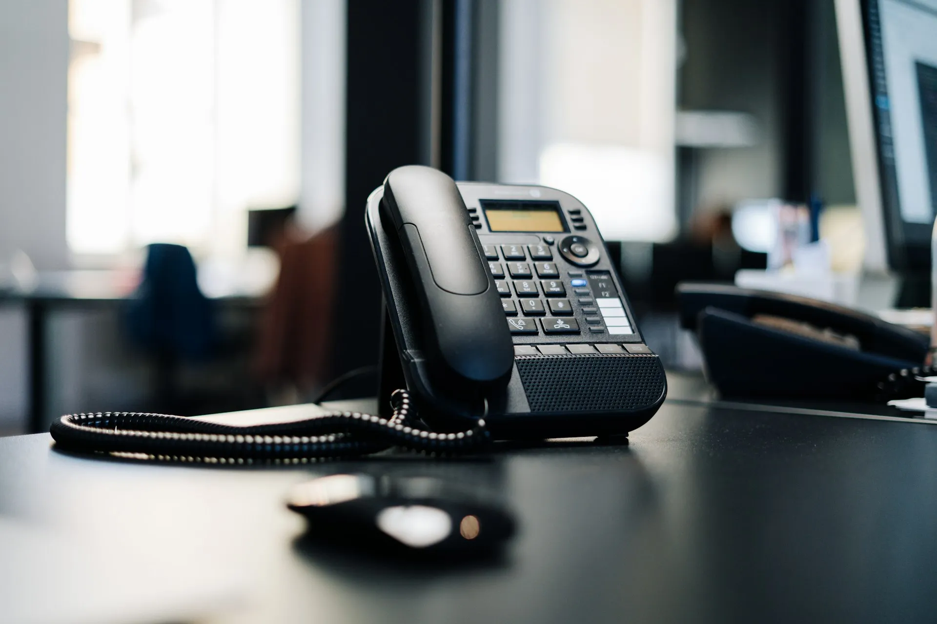 A business desk phone on a dark desk