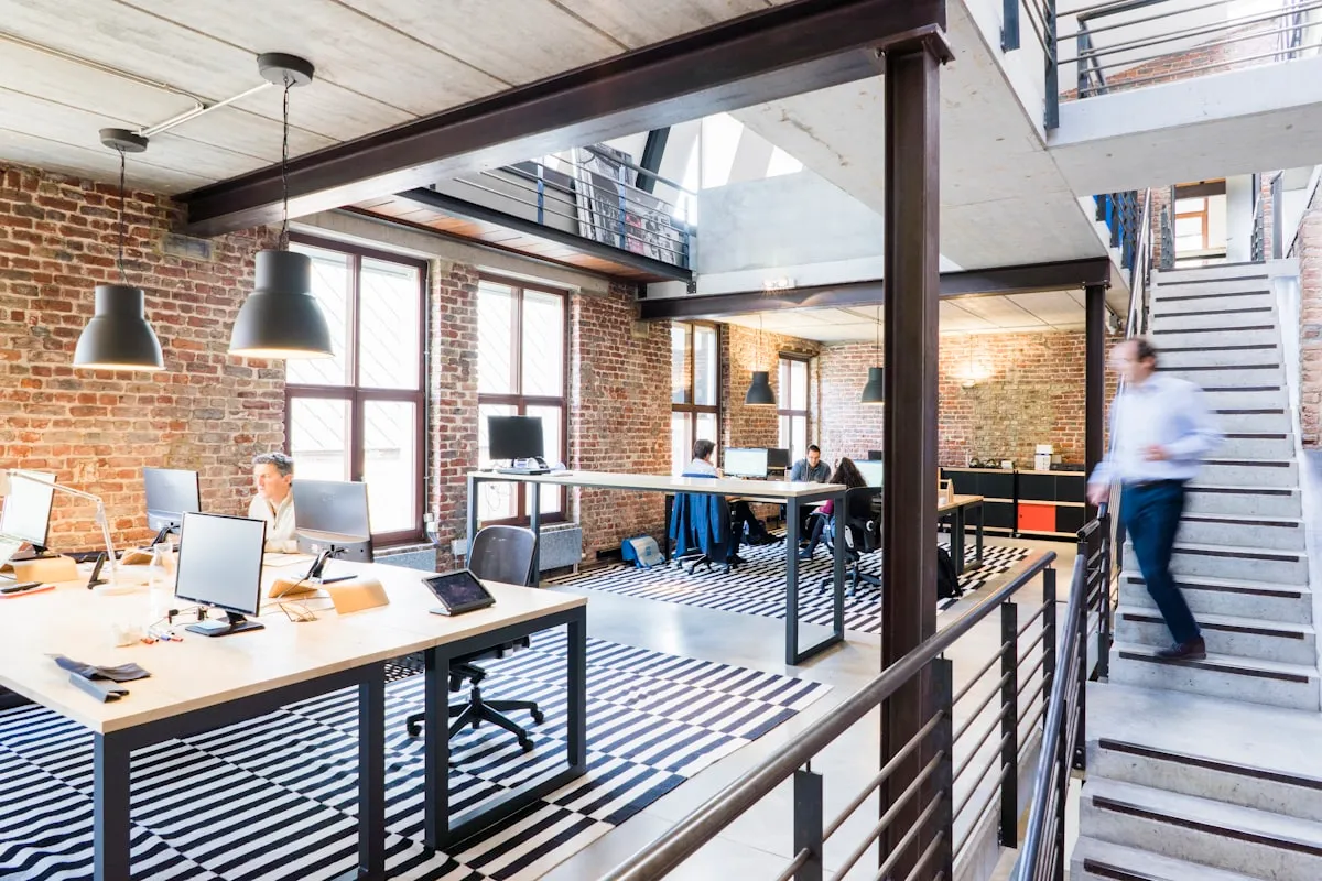 Open-plan loft office with brick walls and an open stair