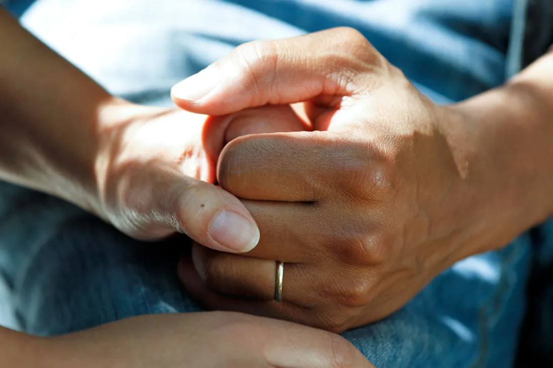Healthcare professional holding a patient's hands in support