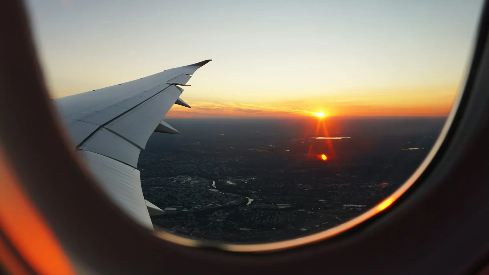 Airplane wing at sunset seen through a cabin window